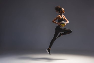 topu tutan ve gri atlama atletik Afro-Amerikan sporcumuz yan görünüm