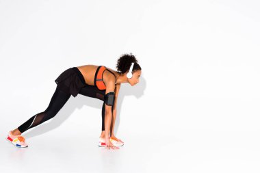 atletik Afro-Amerikan sporcumuz smartphone kol bandı beyaz kopya alanı ile üzerinde çalıştırmak için hazır ve bir kulaklık ile