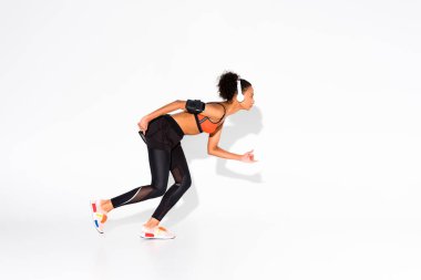 atletik Afro-Amerikan sporcumuz smartphone kol bandı beyaz üzerinde çalıştırmak için hazır ve bir kulaklık ile
