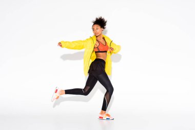 atletik Afro-Amerikan sporcumuz beyaz üzerinde çalışan sarı spor ceketli