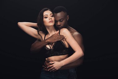 Afrikalı Amerikan adam tutkuyla siyah üzerinde izole dantel sutyen seksi kadın sarılmak