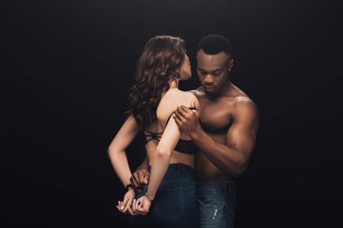 gömleksiz African Amerikan adam kucaklıyor güzel seksi kadın kelepçe içinde siyah üzerinde izole ile kopya alan