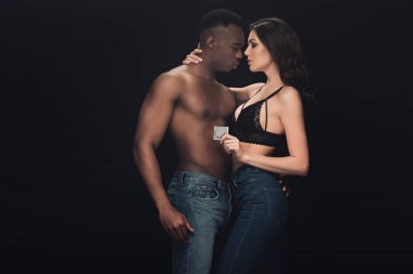 güzel seksi kadın kucaklayan gömleksiz Afrikalı Amerikalı adam ve tutan prezervatif siyah üzerinde izole