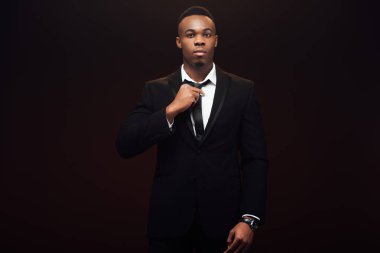 elbise ayarlama kravat ve siyah üzerinde izole kamera bakarak yakışıklı Afrikalı Amerikalı adam 