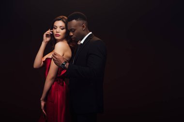 beautiful sensual interracial couple in formal wear posing isolated on black with copy space clipart