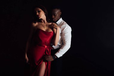 Afrikalı Amerikan adam kopya alanı ile siyah üzerinde izole kırmızı elbise güzel baştan çıkarıcı kadın kucaklayan