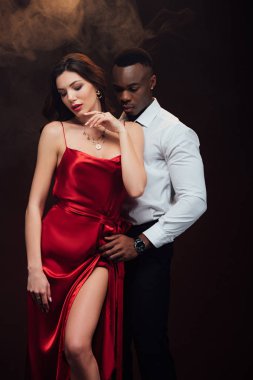 beautiful sensual interracial couple in formal wear posing on black with smoke clipart