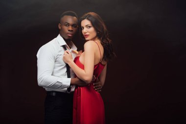 siyah üzerinde izole African American Man kamera ve soyunma gömlek bakarak kırmızı elbise güzel kadın