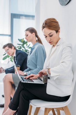 Gözlük kağıt fincan ve adam ile çekici çalışan yakın laptop kullanırken güzel kadın saat bakarak seçici odak 