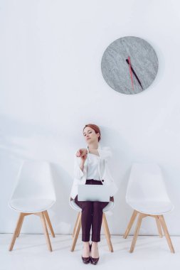 çalışan dizüstü bilgisayar ile sandalyeye oturan ve seyretmek bakıyor