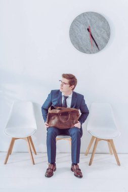 worried man in glasses holding briefcase while waiting job interview  clipart