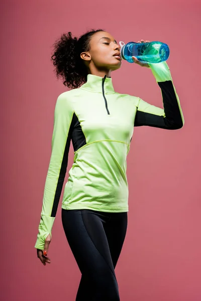 美丽的非洲裔美国女运动员饮用水从运动瓶孤立在棕色 — 图库照片