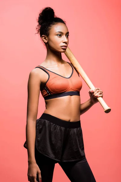 美丽的非洲裔美国女运动员摆姿势与棒球棒孤立珊瑚 — 图库照片