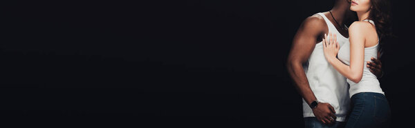 панорамный снимок африканского американца, страстно обнимающего женщину, изолированную на черном с копировальным пространством
