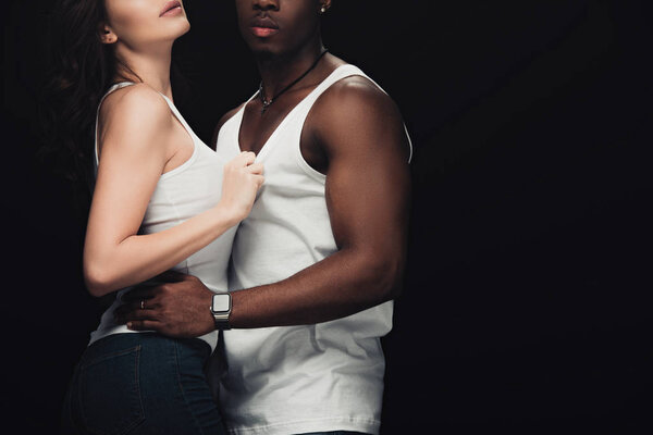 cropped view of seductive interracial couple embracing isolated on black with copy space