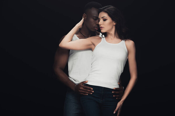 passionate african american man embracing beautiful woman isolated on black