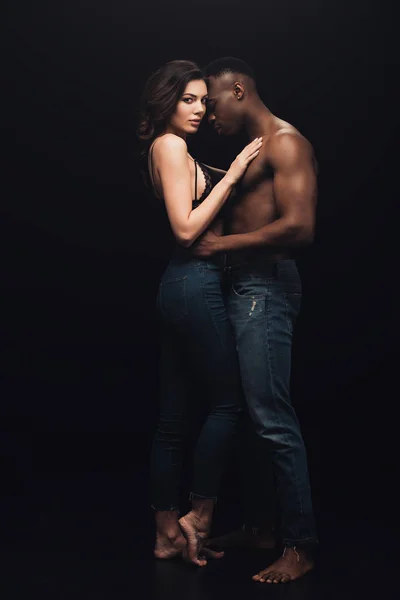 stock image beautiful sexy interracial couple in denim embracing isolated on black