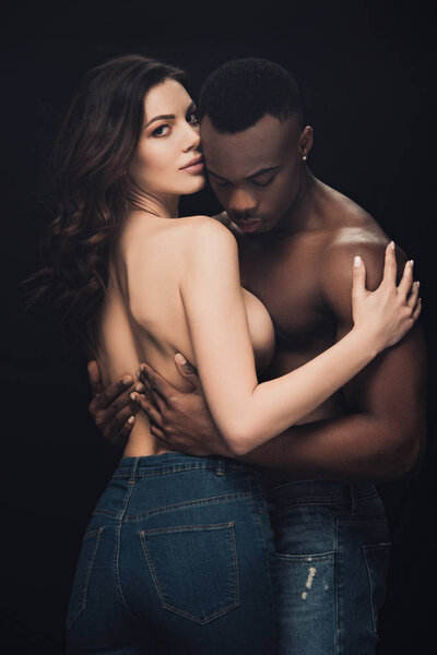 beautiful sensual half-naked interracial couple embracing isolated on black