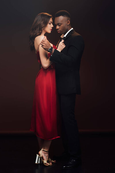 beautiful interracial couple in formal wear posing isolated on black