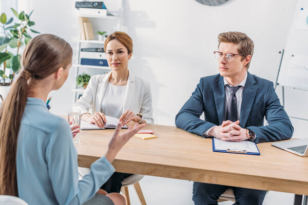 назад взгляд женщины, разговаривающей с рекрутерами во время собеседования
 