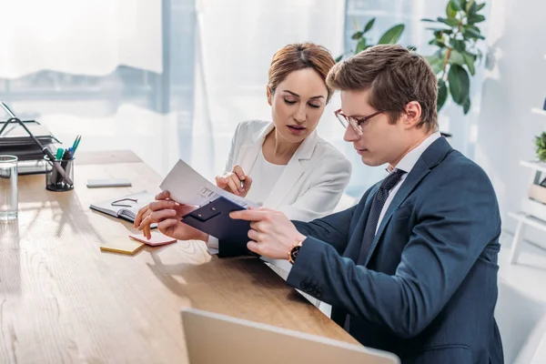 Atractivo Mirando Portapapeles Cerca Compañero Trabajo Gafas Mientras Está Sentado — Foto de Stock