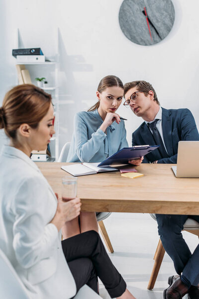 selective focus of recruiters speaking near woman during job interview 