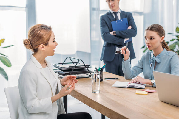 attractive woman talking with recruiter near coworker during job interview 