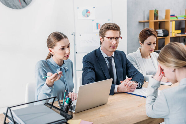 attractive recruiter gesturing while holding pencil and looking at woman covering face 