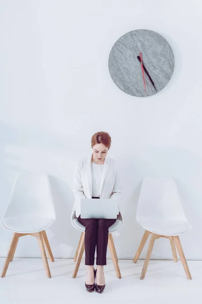 Mulher Atraente Usando Laptop Enquanto Sentado Cadeira Perto Relógio — Fotografia de Stock