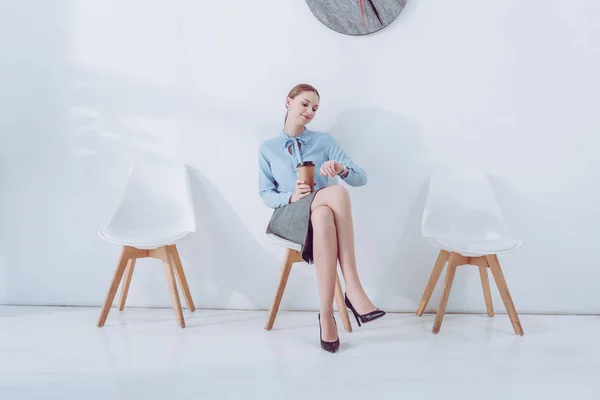 Attractive Employee Holding Paper Cup Looking Watch While Sitting Chair — Stock Photo, Image