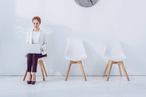 beautiful employee using laptop and sitting on chair 