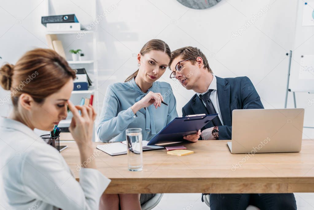 selective focus of recruiters talking and looking at upset woman on job interview 
