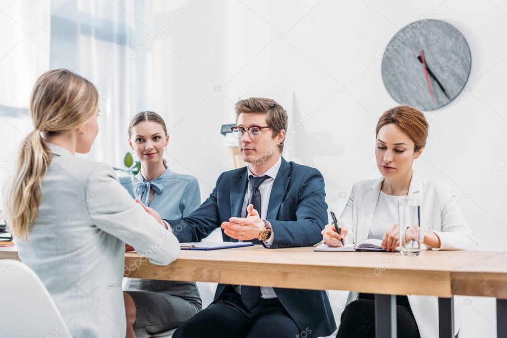 handsome recruiter gesturing while looking at woman on job interview 