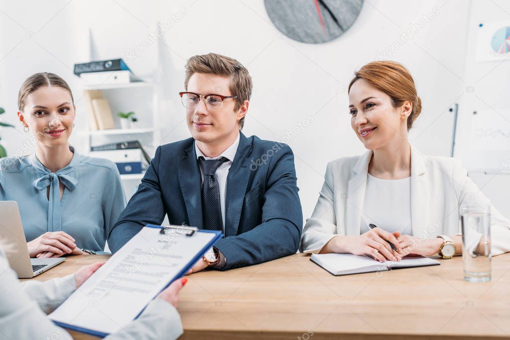 cropped view of woman holding clipboard near cheerful recruiters 