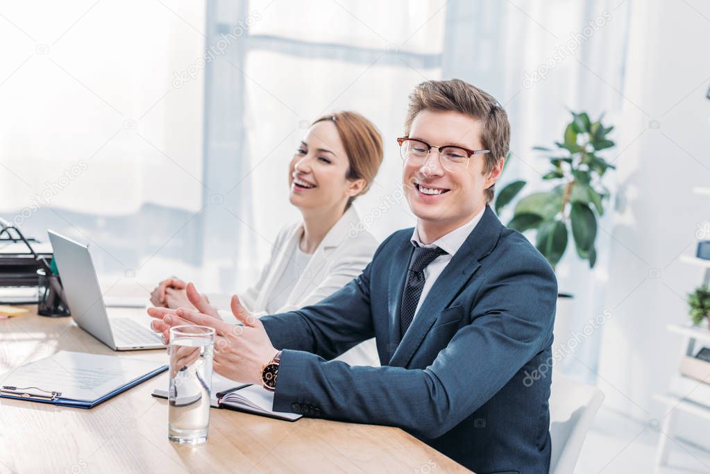 handsome recruiter in glasses smiling near attractive coworker 