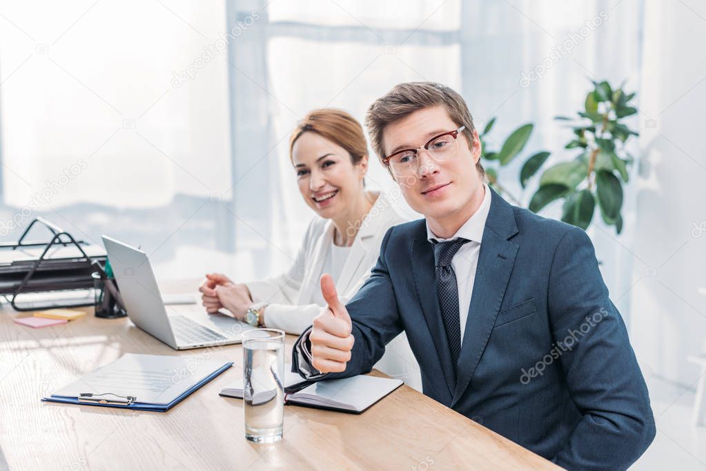 handsome recruiter in glasses showing thumb up near cheerful coworker 