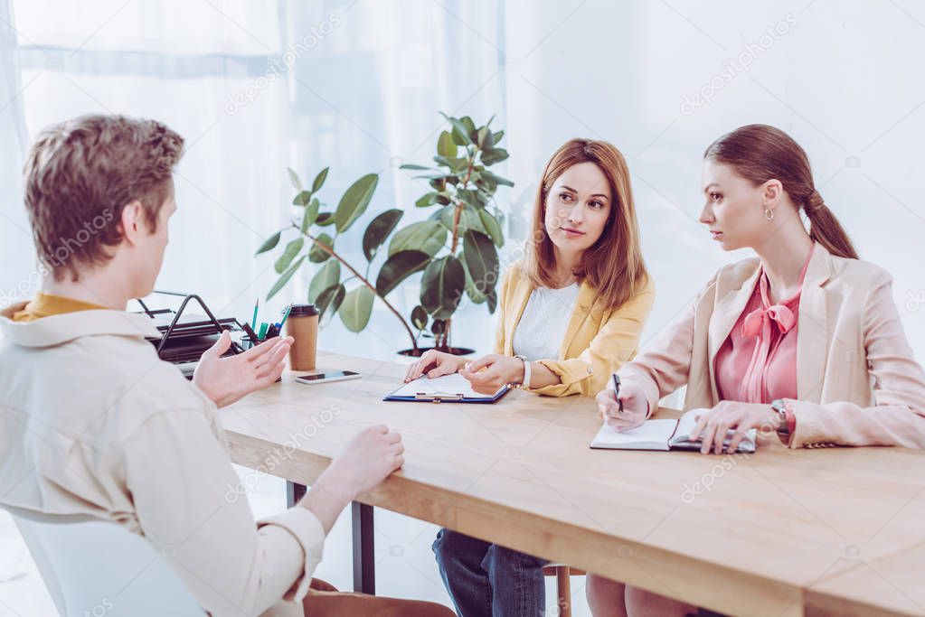 man talking and gesturing near attractive recruiters on job interview 