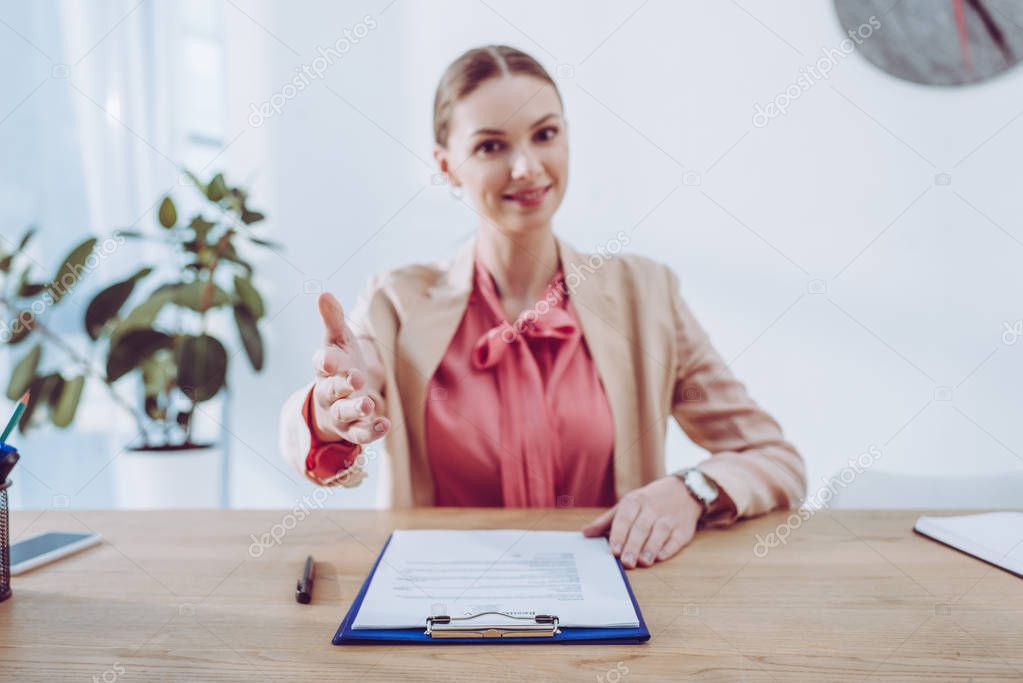 selective focus of hand of attractive recruiter sitting near clipboard 