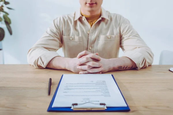 Cropped View Man Sitting Clenched Hands Clipboard Pen — Stock Photo, Image