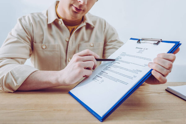 cropped view of recruiter pointing at clipboard with pen 
