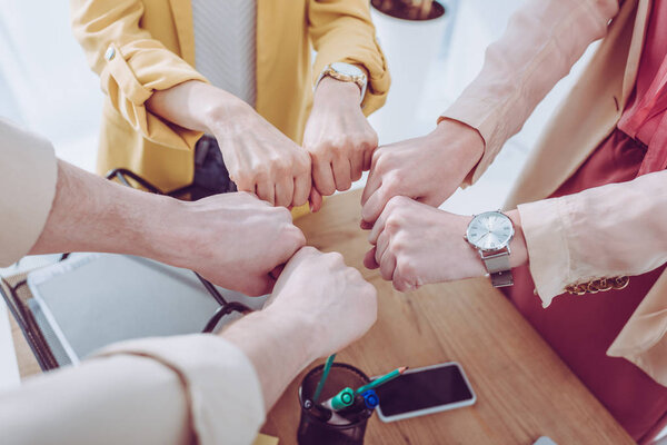 cropped view of women and man giving fist bump in office 