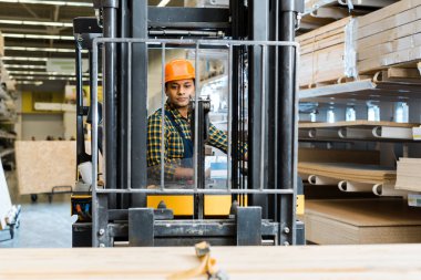 yakışıklı, conentrated Hint Worker seçici odak depoda forklift makinede oturuyor