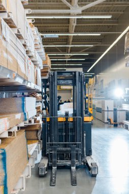forklift machine in warehouse near racks with wooden construction materials clipart