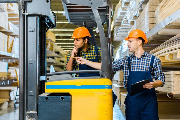 Indian Warehouse Worker Sitting Forklift Machine Colleague Pointing Pencil — Stock Photo, Image