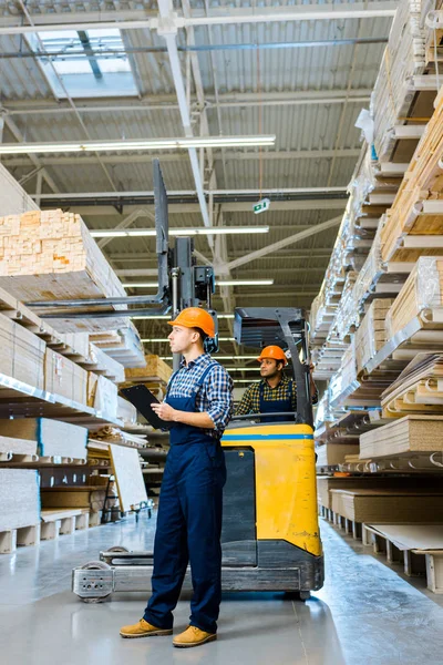 Trabajador Serio Con Portapapeles Pie Cerca Colega Indio Máquina Carretillas — Foto de Stock