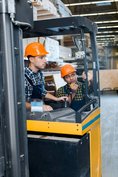 Handsome Attentive Worker Helmet Sitting Forklift Machine Indian Colleague Talking — Stock Photo, Image
