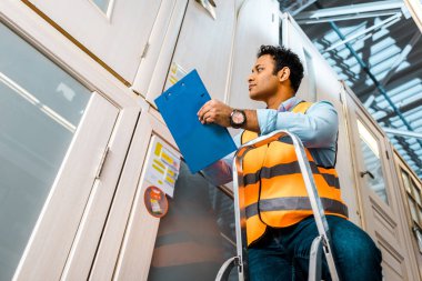 yakışıklı, konsantre Hint ambar işçisi merdiven üzerinde ayakta ve Pano tutarak