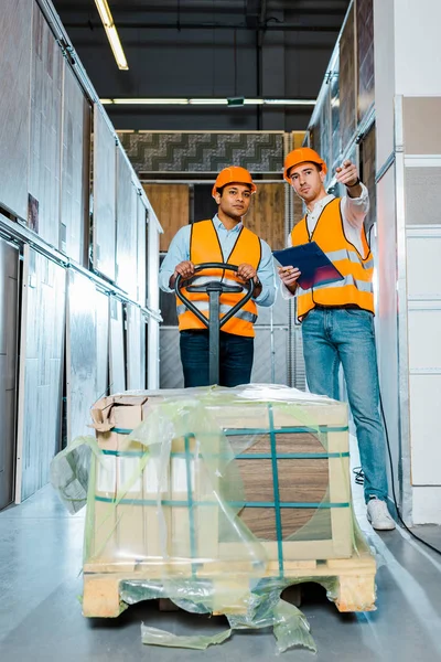 Multiculturele Magazijnmedewerkers Helmen Veiligheids Grootten Staande Buurt Van Pallet Jack — Stockfoto