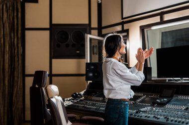 karıştırma konsolu yakınındaki kayıt stüdyosunda alkışlayan çekici ses üreticisi 
