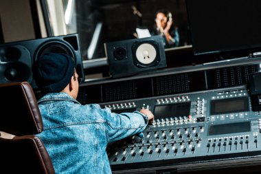 mixing konsolunda çalışan karışık ırk ses yapımcısı seçici odak güzel kadın kayıt stüdyosunda şarkı yaparken